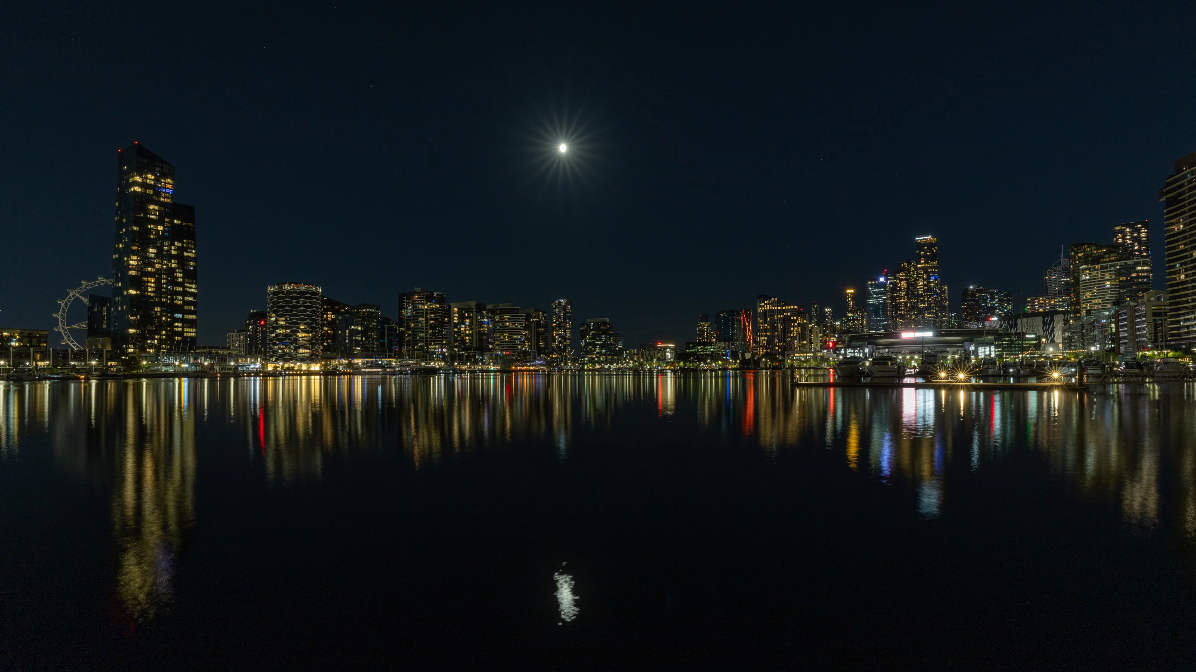 The north-east view from Victoria Harbour Promenade at night, showing the harbour and various buildings
